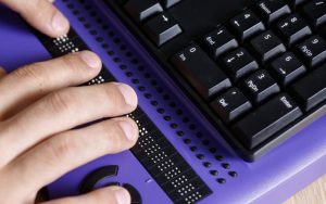Photo: Blind person using computer with braille computer display